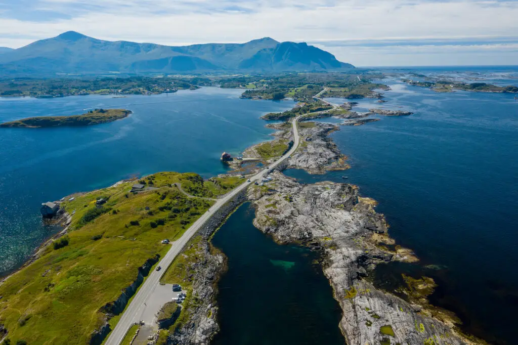 Aerial view of cars traversing the curvy bridges along Atlanterhavsvegen, showcasing the rugged coastal landscape of Norway's west coast.