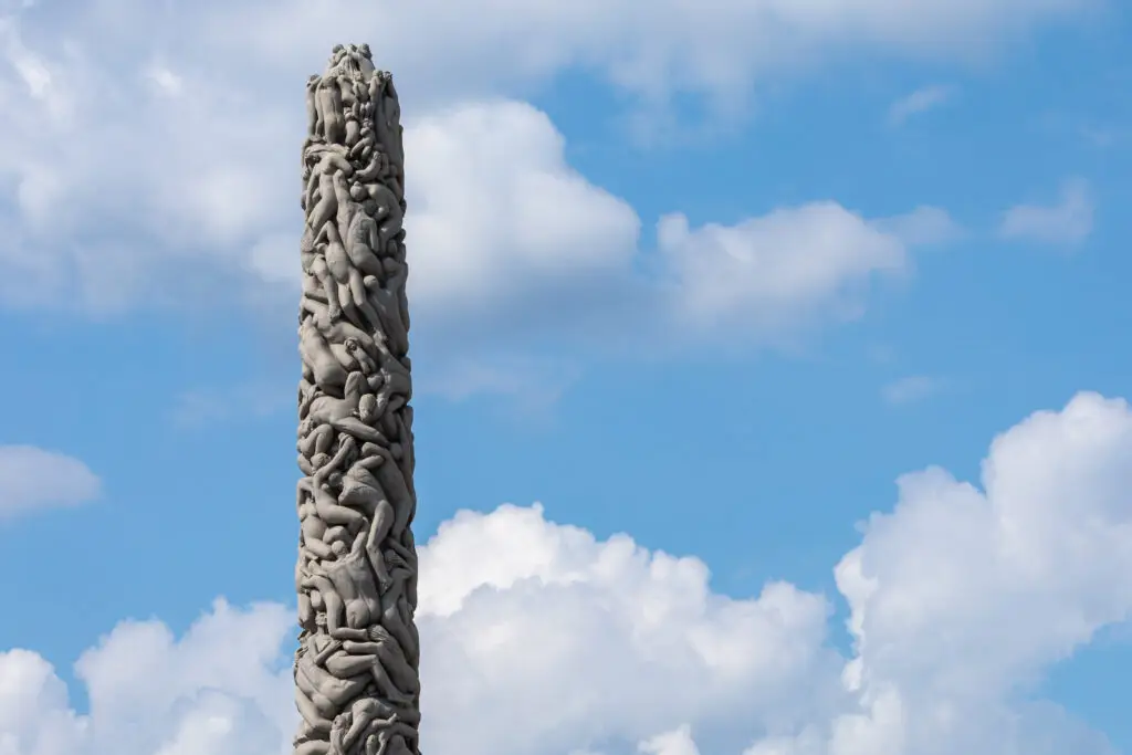 Monolith sculpture of intertwined human figures under a blue sky in Vigeland Park, Oslo Norway, a popular Scandinavian tourist attraction.