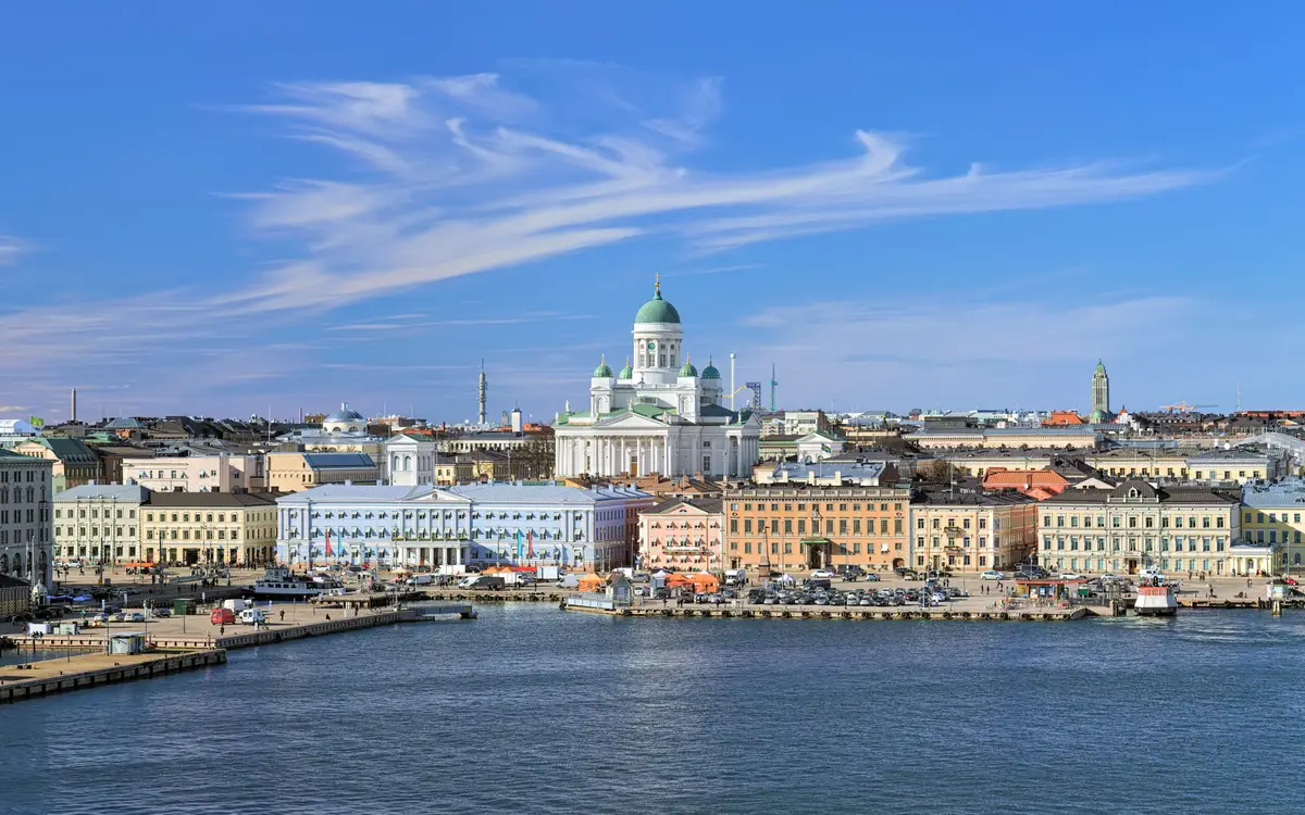 Panoramic view of Helsinki featuring the iconic Helsinki Cathedral, bustling South Harbor, and vibrant Market Square under a blue sky with streaky cirrus clouds, capturing the essence of a sunny spring day in Finland.