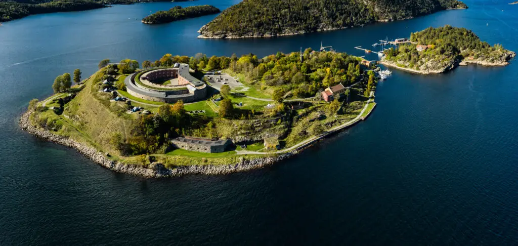 Aerial view of Oscarsborg Fortress in Drøbak, Norway, showcasing its unique star-shaped structure surrounded by the scenic Oslo fjord.