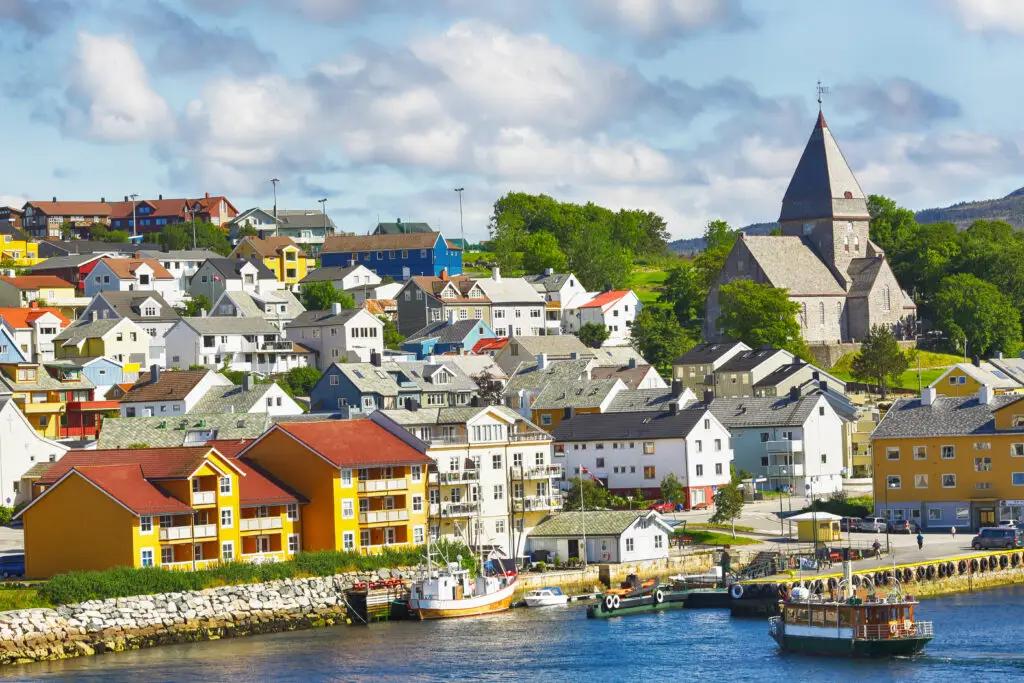 Colorful waterfront scenery of Kristiansund, Norway, featuring historical architecture and boats docked along the quay.