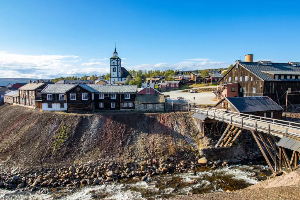 Historic town of Røros in Norway featuring traditional wooden houses and the iconic white church beside a flowing river.