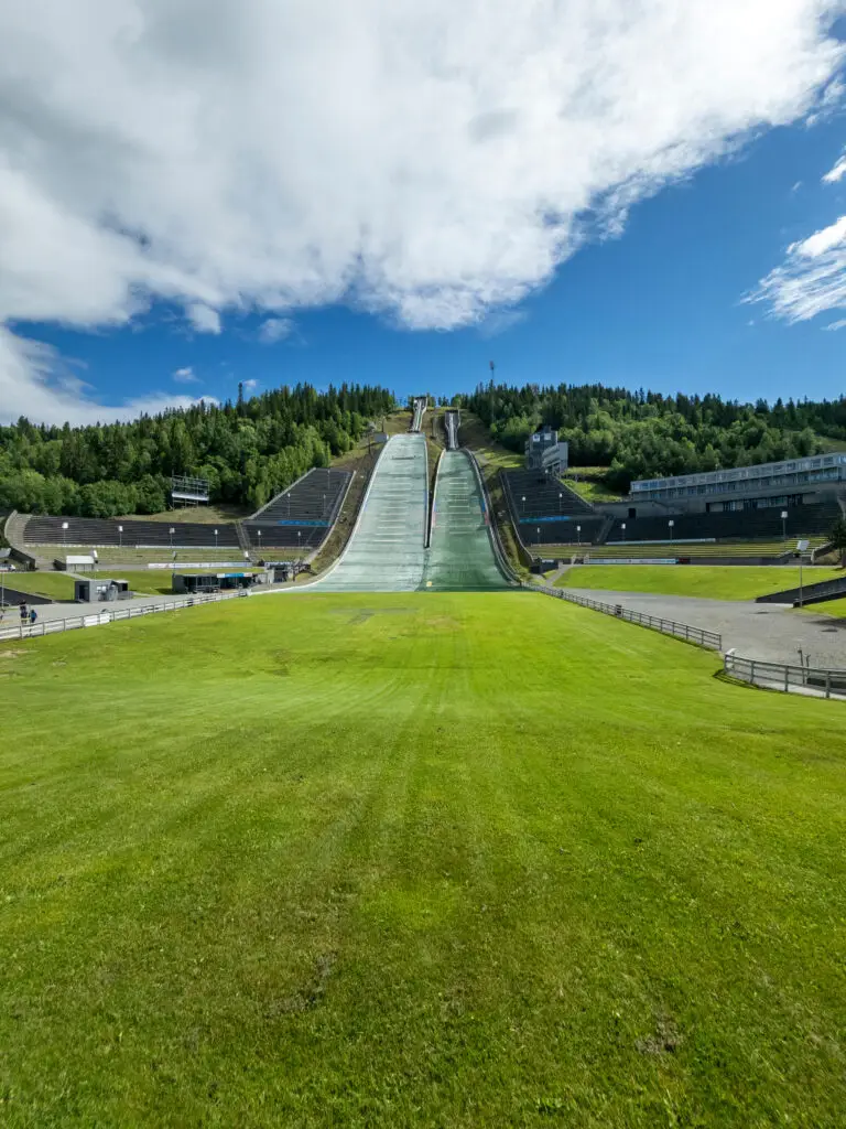 View of Lysgårdsbakkene Ski Jumping Arena in Lillehammer, Norway during spring, showcasing the large ski jump ramps and surrounding green landscape, a famous 1994 Winter Olympic Games venue.