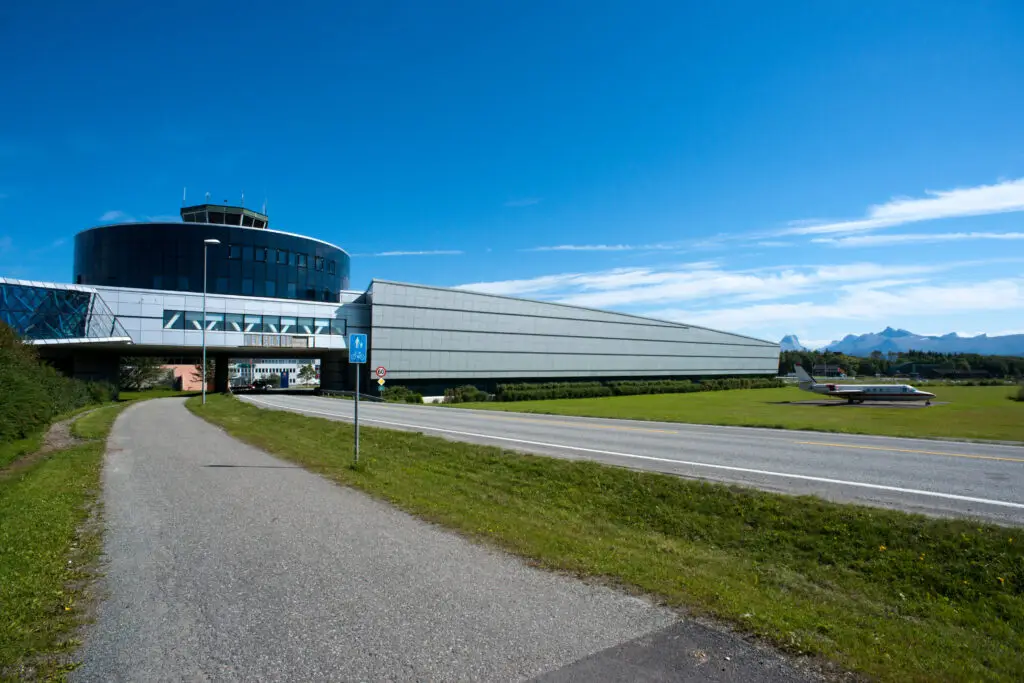 Entrance of the Norwegian Aviation Museum in Bodø, showcasing modern architectural design with clear skies and scenic mountain backdrop, ideal for tourists interested in aviation history.