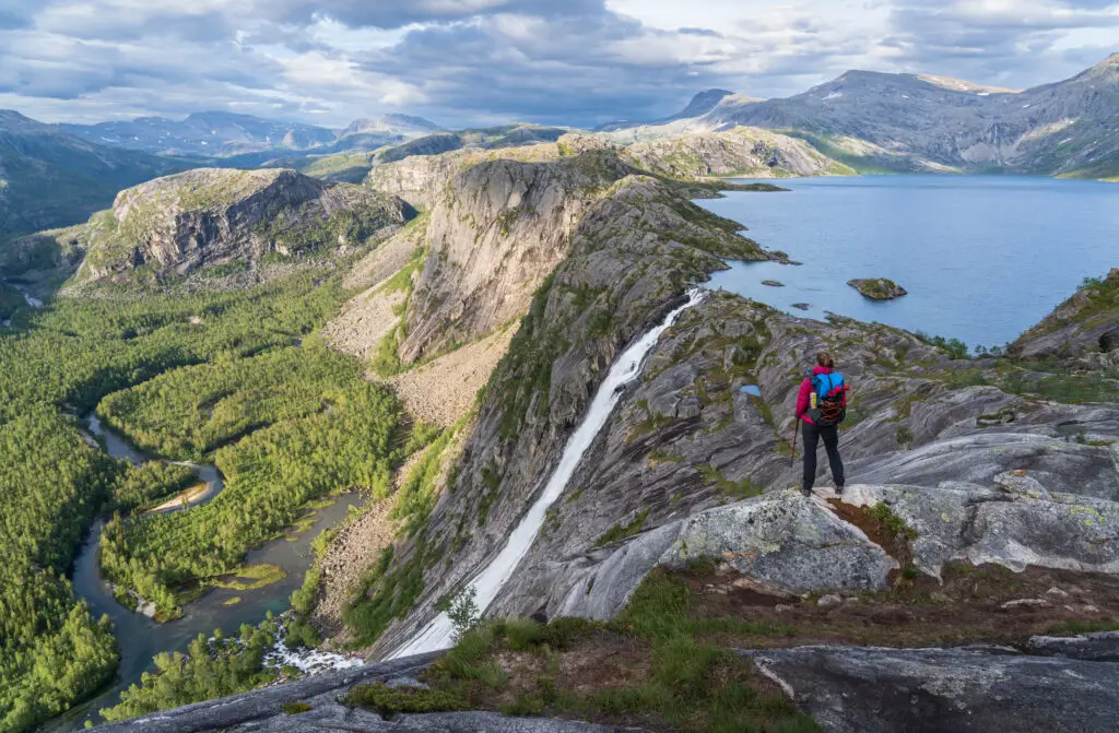 Hiker admiring the majestic waterfall and scenic landscape in Rago National Park, Norway